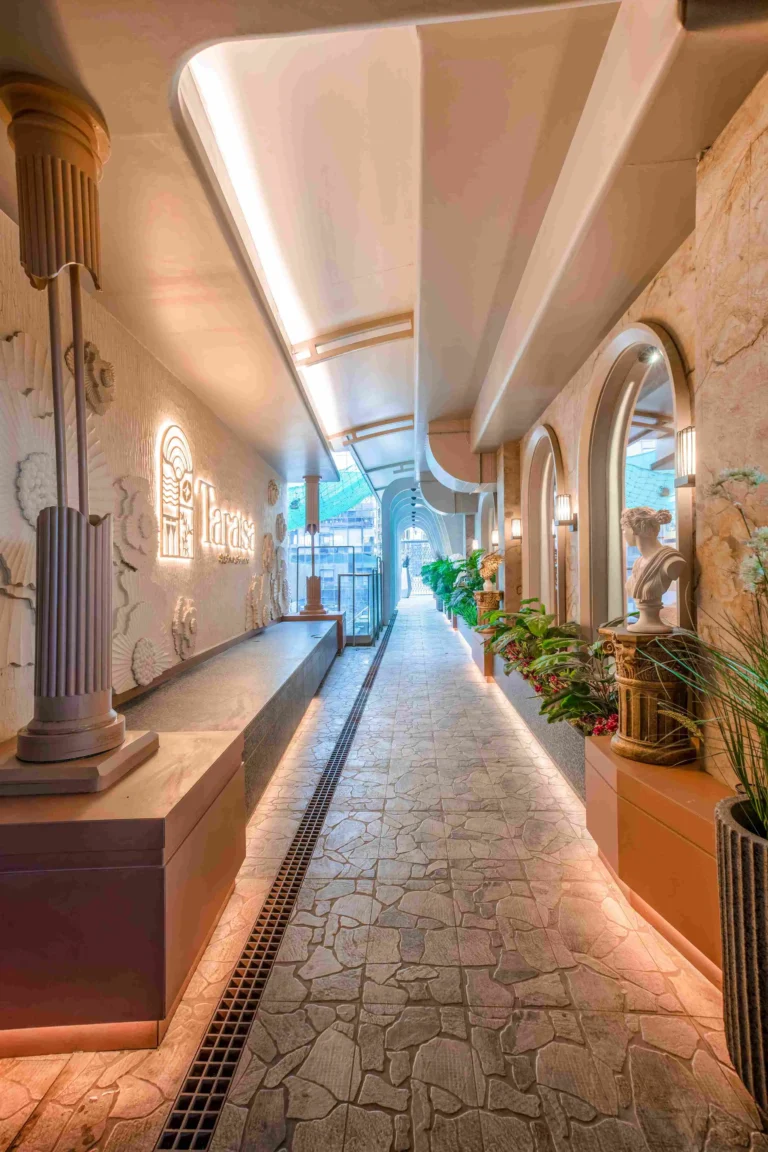 Long corridor with stone arches, plants, and soft warm lighting
